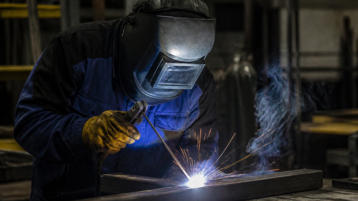 Professional welder using an MMA stick welder to create an arc, illustrating the difference in an MMA vs MIG welder setup.